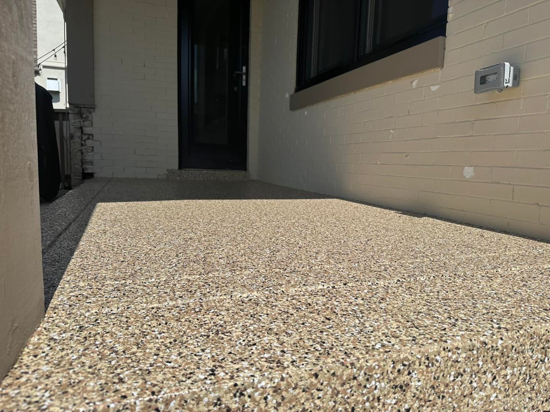 Gray flake patio coating against white brick