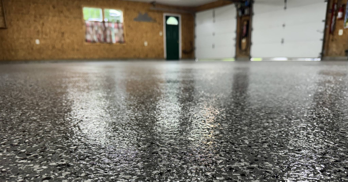 Shiny, speckled flooring in a spacious garage with two closed white doors, wooden walls, and a green entry door.