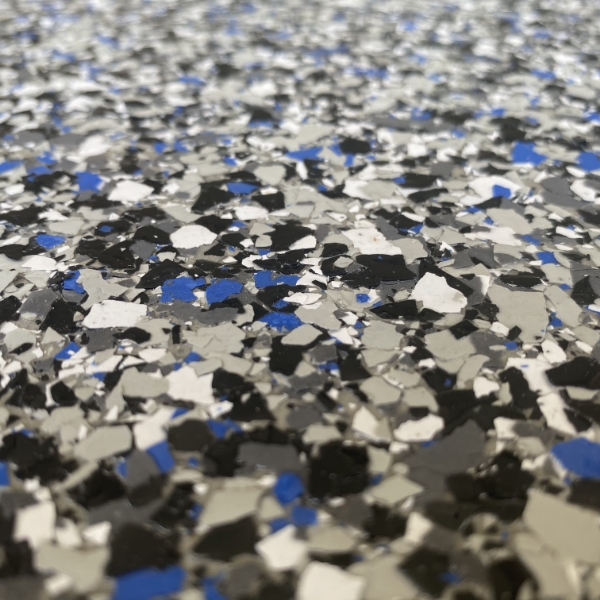 Close-up of a terrazzo surface featuring scattered black, white, and blue stone chips, creating a textured and abstract pattern.